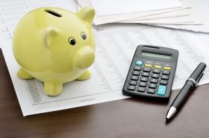 Piggy bank and calculator on top of spreadsheets. Understanding interest rates.