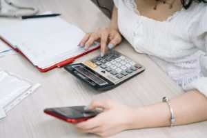Woman using calculator for loan analysis.